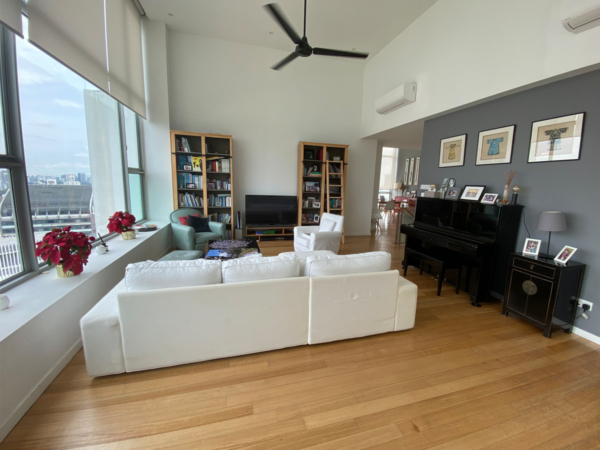 An airy high-rise living room with expansive windows, plush seating, and a grand piano, exuding a blend of comfort and elegance. Perched in a high-rise building, this living room is a testament to sophisticated urban living. Expansive windows invite the outside in, flooding the room with light and offering a backdrop of the bustling city below. The layout promotes relaxation and entertainment, with a plush white sectional sofa facing a sleek TV setup, complemented by a cozy teal armchair. On the far end, a polished black grand piano awaits, promising musical interludes. Bookshelves brimming with books add a personal touch, suggesting a love for literature and culture. Darker walls create a striking contrast, providing the perfect canvas for an array of framed art. This space perfectly encapsulates a modern lifestyle that cherishes both the comforts of home and the allure of city life.