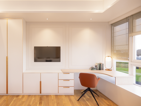 A well-organized home office with a white built-in desk and cabinetry, a terracotta chair, and natural light from a window with blinds. This image captures a serene home office space that balances functionality with sophisticated design. The room is bathed in natural light from a large window adorned with sleek blinds, which gently filter the light and offer a view of the outdoors. A white built-in desk extends along the window's length, providing a spacious work area. The desk is flanked by white cabinetry with subtle detailing and golden handles that add a touch of warmth and luxury. Above the desk, a flat-screen television is mounted on a recessed panel, which adds depth to the space. An elegant terracotta chair with a black base offers a comfortable seating option, its color providing a striking contrast against the room's neutral palette. The herringbone-patterned wooden floor complements the furniture's clean lines, while a minimalist table lamp with a round mirror surface enhances the ambiance. This home office design promotes a clutter-free environment that encourages focus and productivity, reflecting contemporary trends in interior design.