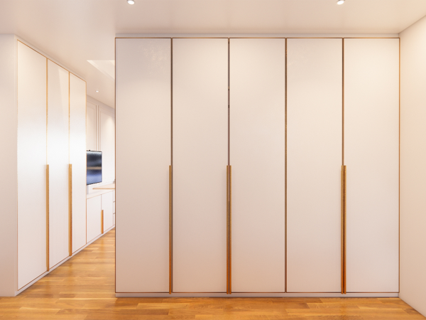 Minimalistic custom-built wardrobe with frosted glass panels and wooden accents in a bright interior. This image showcases a contemporary and spacious room featuring a wall-to-wall custom-built wardrobe. The wardrobe's design exudes minimalism and functionality with its frosted glass panels, which not only add an element of privacy but also a subtle texture that contrasts with the smooth, matte finish of the surrounding frame. Warm wooden handles vertically align with the doors, offering a natural touch and easy access, and they complement the room's herringbone-patterned hardwood floor. The lighting in the room casts a soft glow, highlighting the clean lines and the simplicity of the design. This storage solution perfectly encapsulates modern living where form meets function, providing ample space while maintaining a sense of understated elegance.