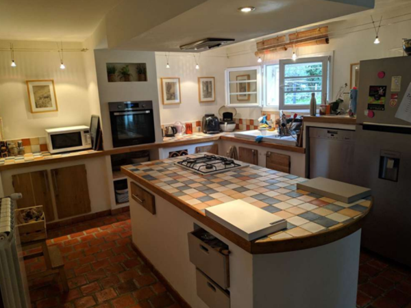 A dated kitchen with tiled countertops, wooden cabinets, and a tiled floor.