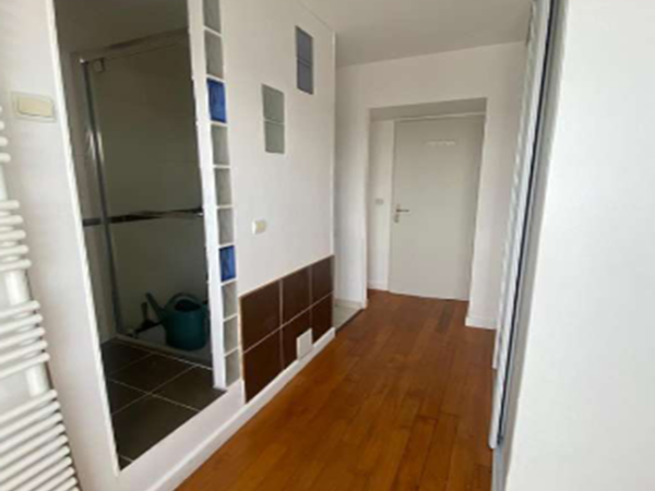 A cluttered storage room with various items and a glass block wall.